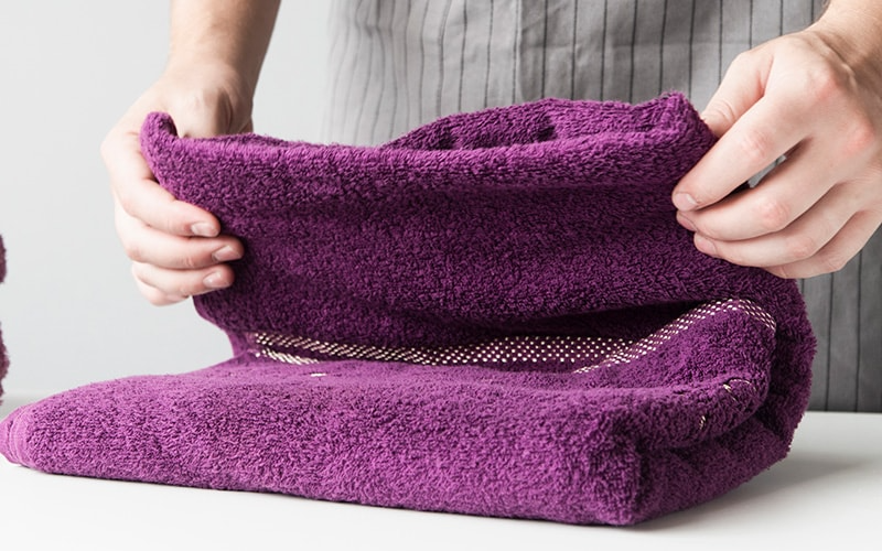 COVER Person folding purple microfiber towel