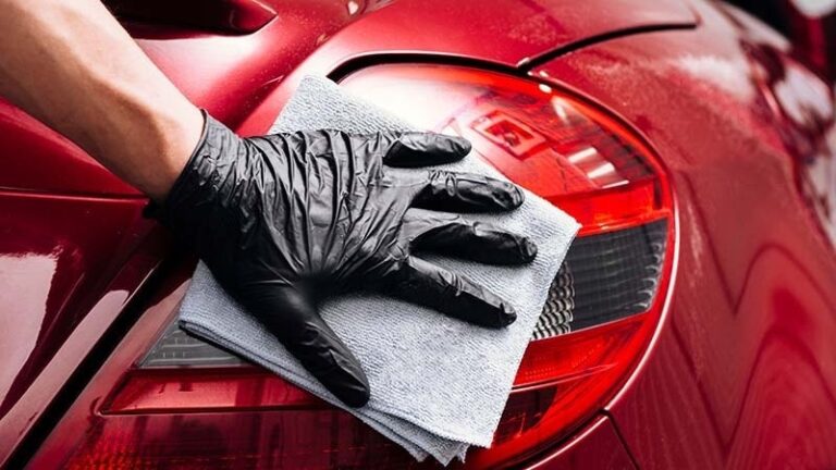 A man wiping a car tail taillight clean
