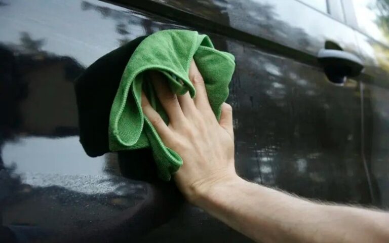 A person cleans a car with a microfiber cloth.