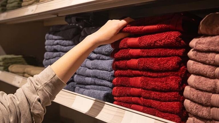 A woman picking up towels from the shelf
