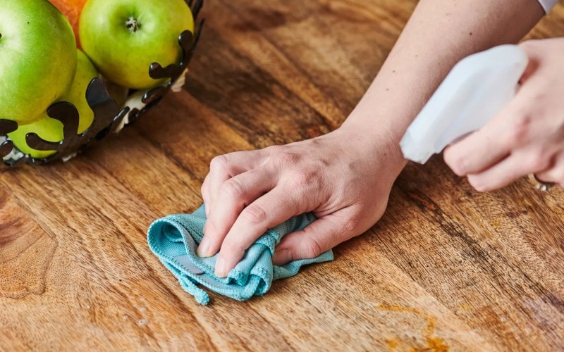 A woman scrubbing the floor with a microfiber cloth.