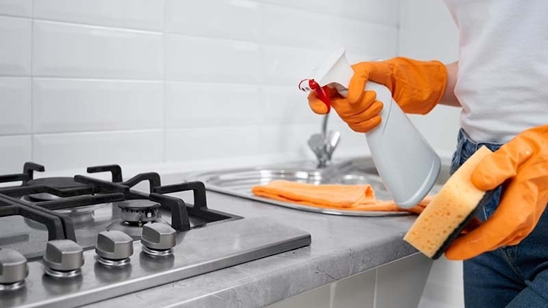 A woman scrubbing the stove top