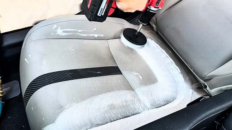Man using a drill brush to shampoo car seats by Highlands Auto Detailing